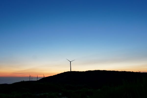 Moinhos eólicos ao pôr do sol, simbolizando investimentos em energias renováveis e sustentabilidade no âmbito do Portugal 2030